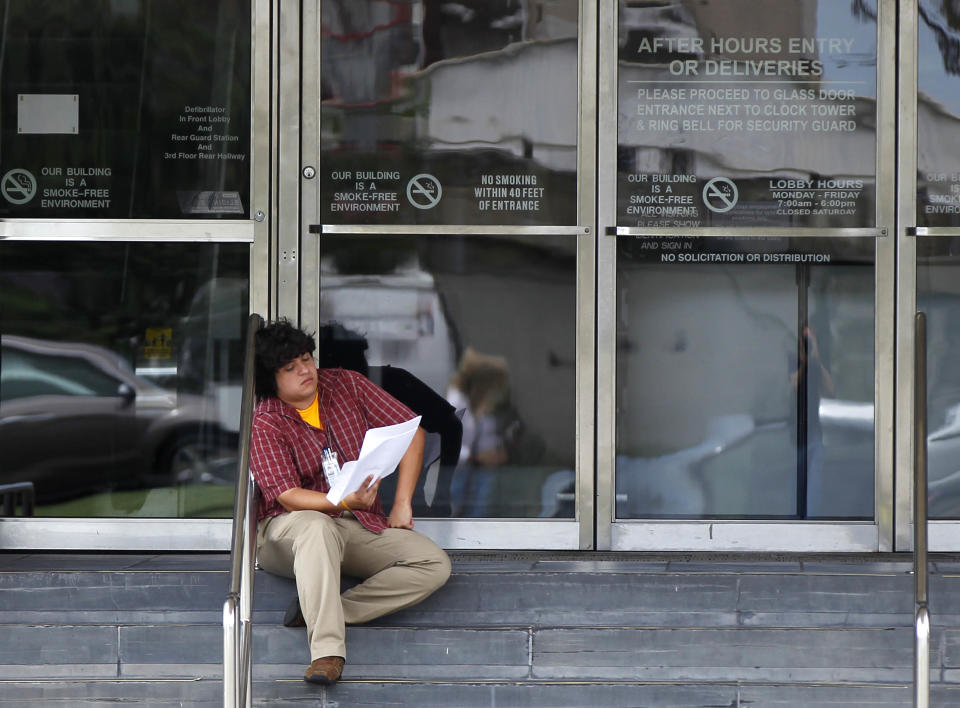 Time-Picayune reporter Ramon Vargas sits on the front steps of the newspaper's offices as he reads his job offer packet after being retained by the newspaper in New Orleans, Tuesday, June 12, 2012. The Times-Picayune is laying off 200 employees as one of the nation's oldest daily newspapers prepares to print just three days a week. The layoffs amount to about half of the newsroom's 169 employees. Advertising, circulation and other departments also were affected at the 175-year-old newspaper. (AP Photo/Gerald Herbert)