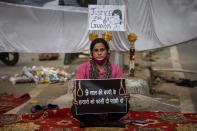 Tina Verma, 27, a social activist, holds a placard which reads, "Hang the killers of 9-year old child" at a demonstration site outside a crematorium where a 9-year-old girl from the lowest rung of India's caste system was, according to her parents and protesters, raped and killed earlier this week, in New Delhi, India, Thursday, Aug. 5, 2021. (AP Photo/Altaf Qadri)