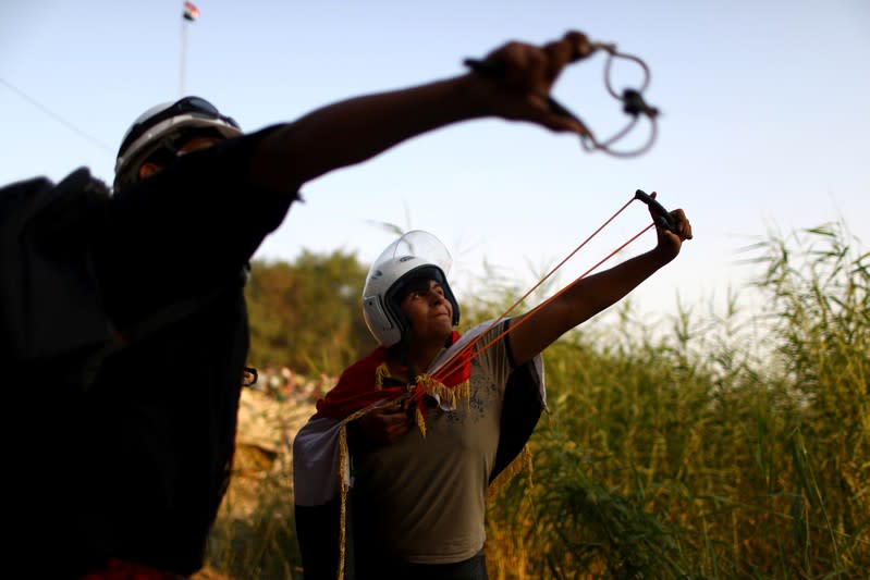 Iraqi demonstrators use sling shots during the ongoing anti-government protests in Baghdad