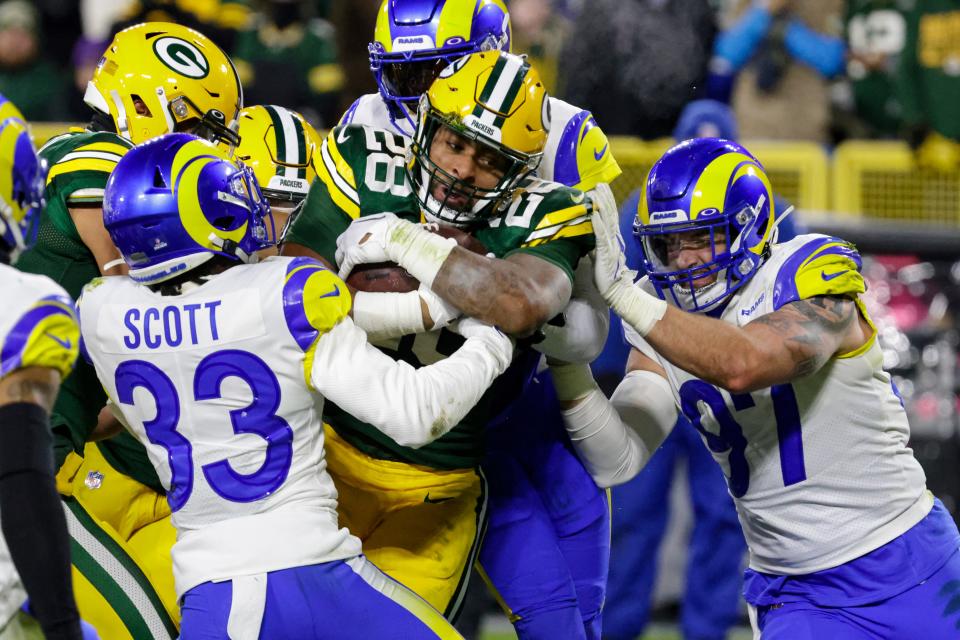 Green Bay Packers running back AJ Dillon (28) runs in for a touchdown between Los angles Rams cornerback Nick Scott (33) and defensive tackle Michael Hoecht (97) in the first half of an NFL football game in Green Bay, Wis. Monday, Dec. 19, 2022. (AP Photo/Mike Roemer)