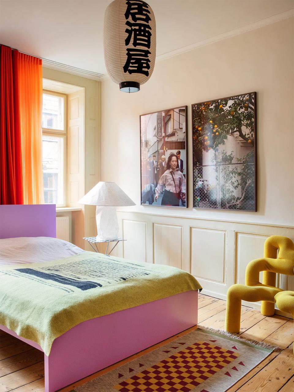 Teen bedroom with yellow curtains, pink bed, and paper lantern light.