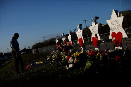 A man mourns next to the crosses and Stars of David placed in front of the fence of the Marjory Stoneman Douglas High School to commemorate the victims of the mass shooting, in Parkland, Florida, U.S., February 19, 2018. REUTERS/Carlos Garcia Rawlins