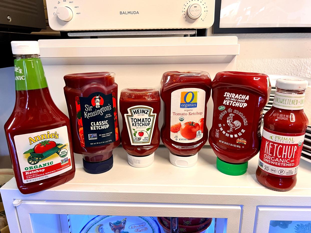 Six brand bottles of ketchup lined up on kitchen counter