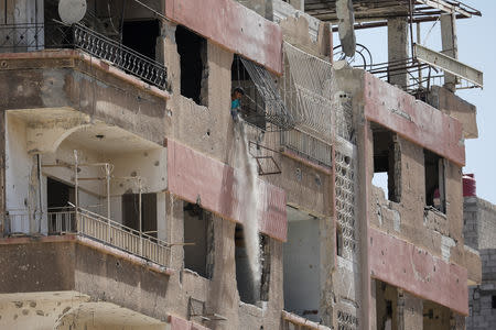 A man throws out debris from an apartment building in Douma, outside Damascus, Syria, September 17, 2018. REUTERS/Marko Djurica