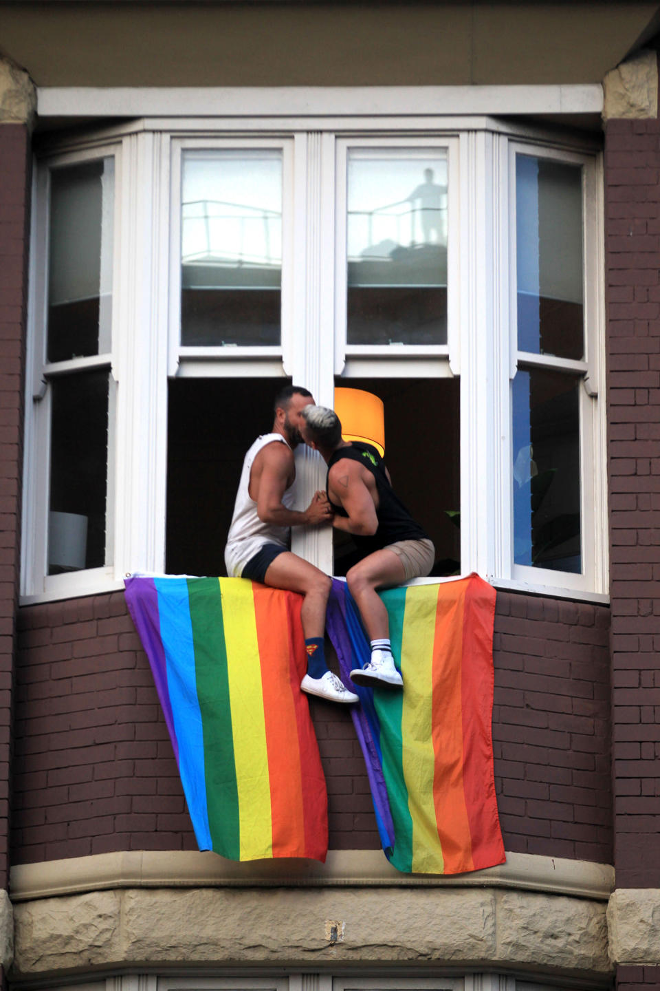 <p>A couple kiss as they sit at their window as crowds supporting the Same Sex Marriage Survey march down Oxford St., and into the city whilst a same sex couple embrace above in a window on Nov. 15, 2017 in Sydney, Australia. (Photo: James Alcock/Getty Images) </p>