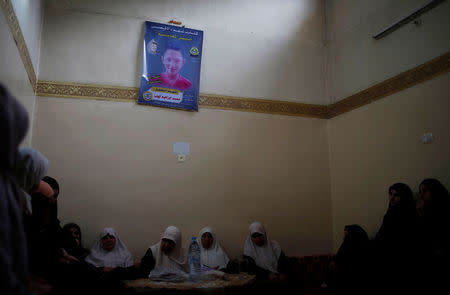 Relatives of Mohammed Ayoub, 14, a Palestinian boy who was shot dead by Israeli troops during clashes at the Israel-Gaza border, sit under a poster of him at his house in the northern Gaza Strip April 21, 2018. REUTERS/Mohammed Salem