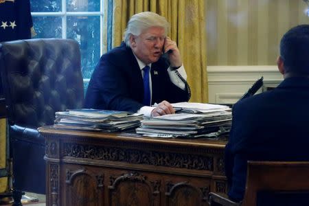 U.S. President Donald Trump speaks by phone with Germany's Chancellor Angela Merkel in the Oval Office at the White House in Washington, U.S. January 28, 2017. REUTERS/Jonathan Ernst