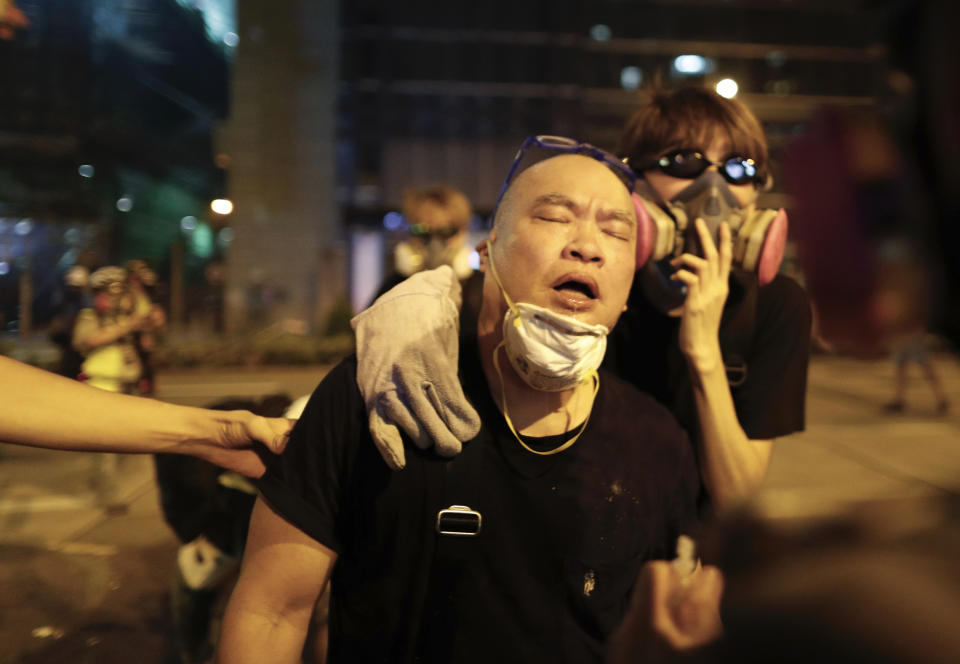 A protester is overcome by tear gas near the Shum Shui Po police station in Hong Kong on Wednesday, Aug. 14, 2019. German Chancellor Angela Merkel is calling for a peaceful solution to the unrest in Hong Kong amid fears China could use force to quell pro-democracy protests.(AP Photo/Vincent Yu)