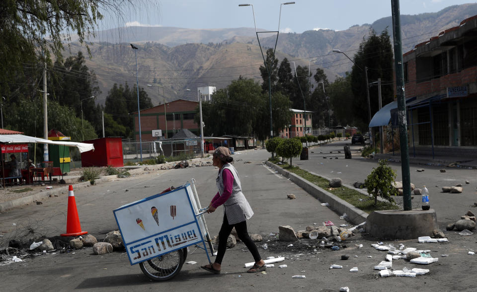 An ice cream vender rolls her cart past a barricade created by anti-government protesters in Sacaba, Bolivia, Wednesday, Nov. 20, 2019. Bolivia has been in a state of turbulence since a disputed Oct. 20 vote. Former President Evo Morales resigned Nov. 10, but his supporters oppose the interim government that took his place. (AP Photo/Juan Karita)