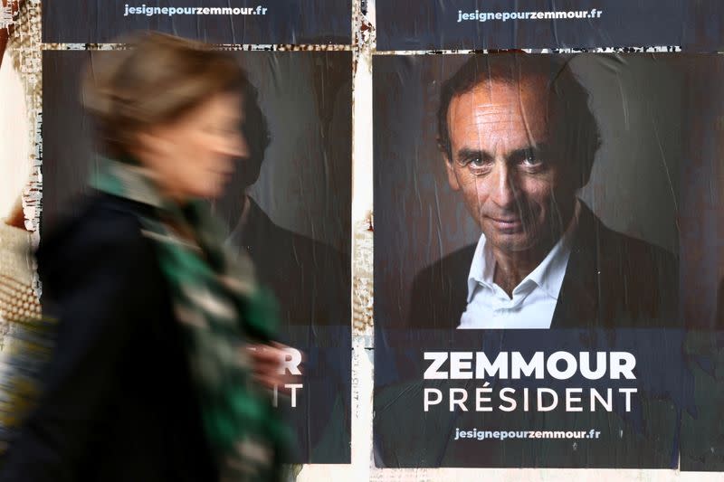 A woman walks past posters in support of French far-right commentator Eric Zemmour in Paris