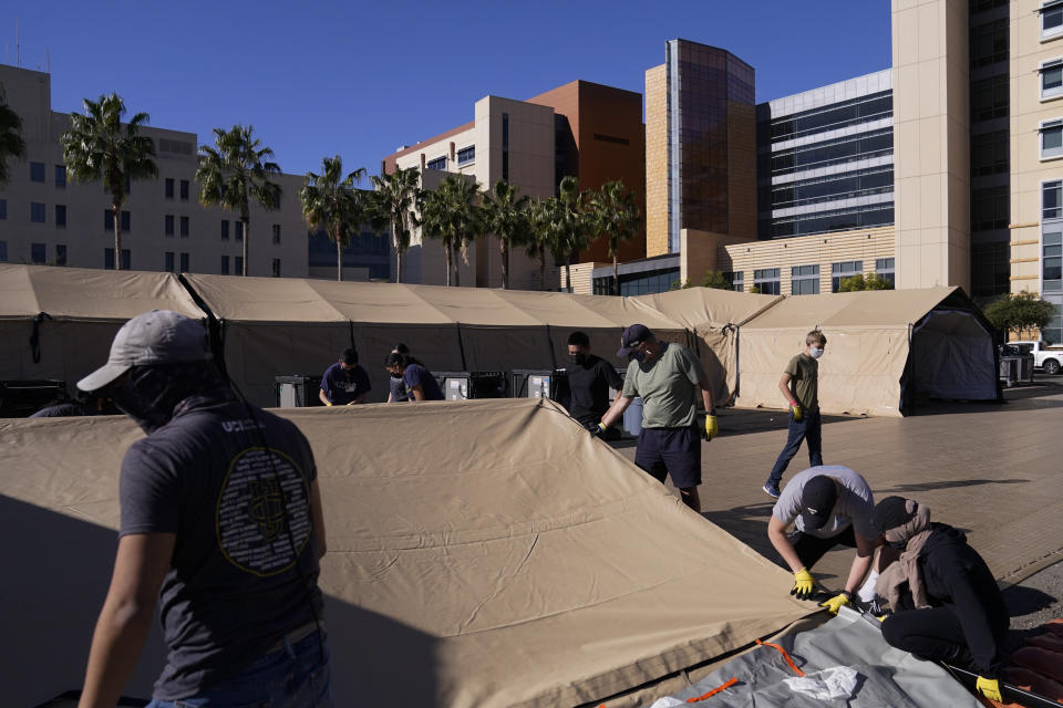Volunteers help set up a mobile field hospital at UCI Medical Center, Monday, Dec. 21, 2020, in Orange, Calif. California's overwhelmed hospitals are setting up makeshift extra beds for coronavirus patients, and a handful of facilities in hard-hit Los Angeles County are drawing up emergency plans in case they have to limit how many people receive life-saving care. (AP Photo/Jae C. Hong)