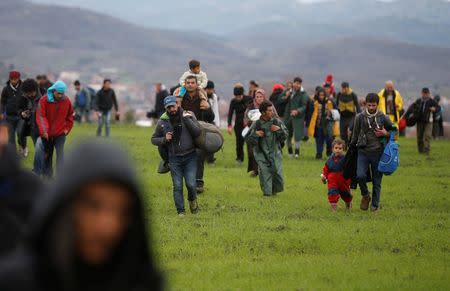 Migrants walk through a field looking for a way to cross the Greek-Macedonian border, near the village of Idomeni, Greece, March 14, 2016. REUTERS/Stoyan Nenov