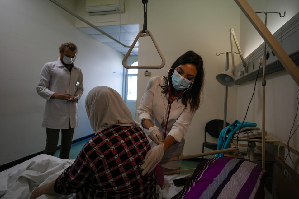 Ghaidaa al-Saddik, internal medicine resident doctor checks on a patient at government-run Rafik Hariri University Hospital in Beirut, Lebanon, Wednesday, Aug. 11, 2021. Many private hospitals, who offer 80% of Lebanon's medical services, are shutting down because of lack of resources or turning away patients who can't pay. (AP Photo/Hassan Ammar)