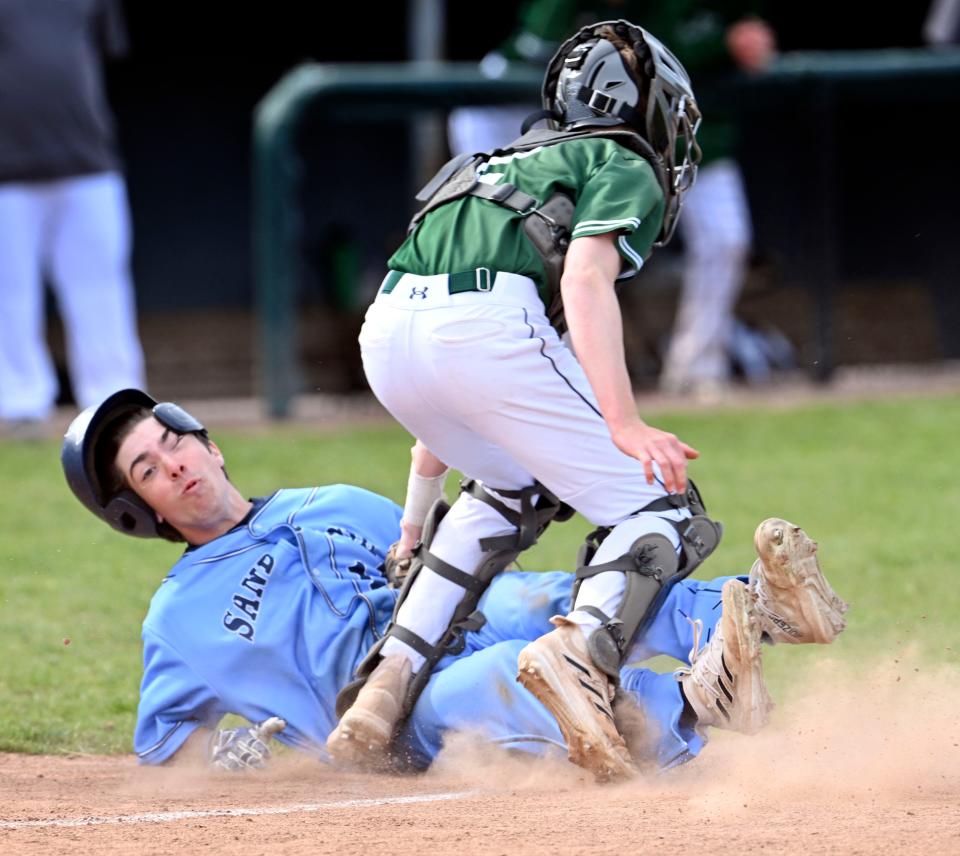 Dennis-Yarmouth catcher Lincoln Slade tumbles over Ty Creighton of Sandwich slides into home ending the side in the first inning on Friday, April 28, 2023.