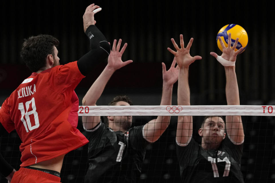 Egor Kliuka, of the Russian Olympic Committee,, left, spikes the ball past Canada's Stephen Timothy Maar and Canada's Graham Vigrass during the men's volleyball quarterfinal match between Canada and Russian Olympic Committee at the 2020 Summer Olympics, Tuesday, Aug. 3, 2021, in Tokyo, Japan. (AP Photo/Frank Augstein)