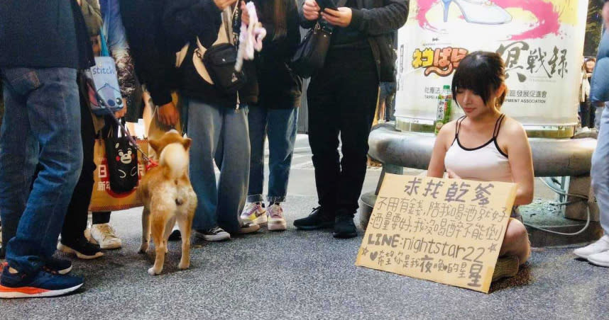 26日晚間的西門町，出現一位身穿小可愛的女子拿著紙牌徵求乾爹。（圖／翻攝自爆料公社2館）