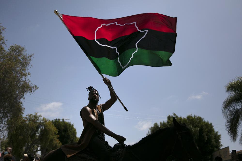 Rein Morton waves a Pan-African flag on horseback during a Juneteenth celebration in Los Angeles, Friday, June 19, 2020. (AP Photo/Jae C. Hong, File)