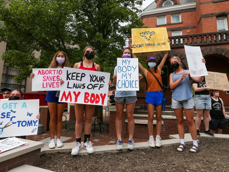 Abortion rights protesters hold signs.