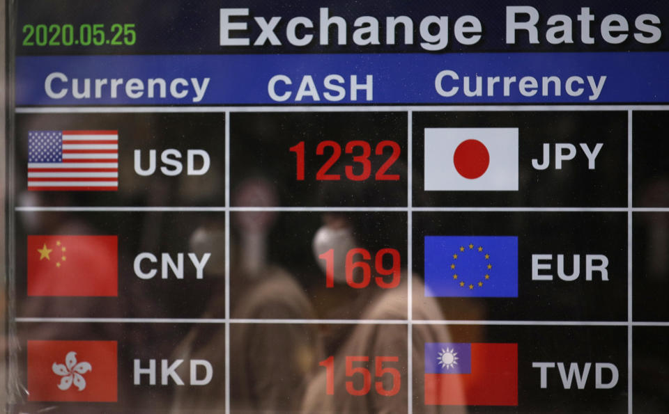 A woman wearing a face mask is reflected on an electronic foreign currency exchange rates in downtown Seoul, South Korea, Monday, May 25, 2020. Asian shares are mostly higher, with Tokyo stocks gaining on expectations that a pandemic state of emergency will be lifted for all of Japan. But shares fell in Hong Kong on Monday after police used tear gas to quell weekend protests over a proposed national security bill for the former British colony. (AP Photo/Lee Jin-man)