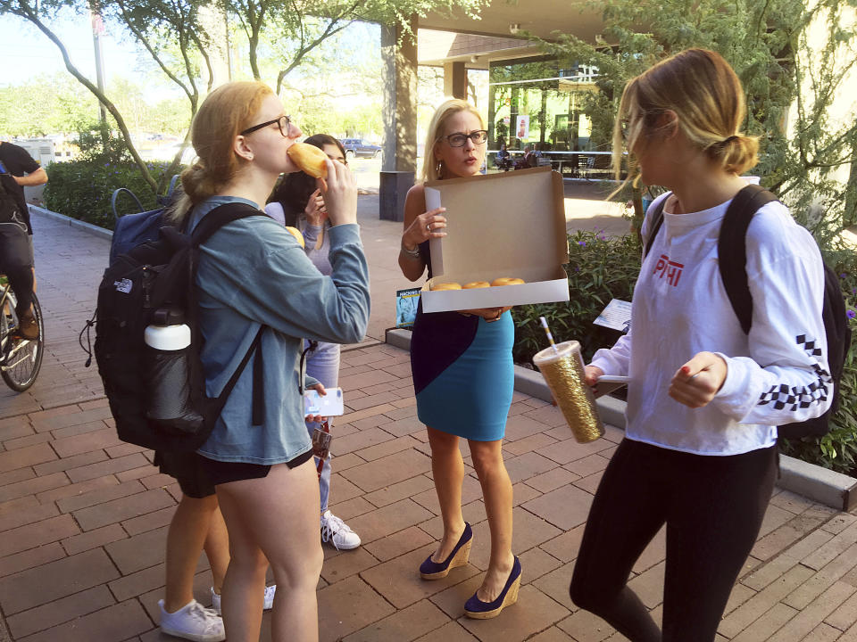 CORRECTS TO DOWNTOWN PHOENIX CAMPUS NOT TEMPE - Democratic Senate candidate Kyrsten Sinema hands out doughnuts to Arizona State University students on the campus in downtown Phoenix, Monday, Nov. 5, 2018. Sinema, a congresswoman who teaches at the school, closed out her campaign against Republican Rep. Martha McSally with a dash across the Phoenix metro area. (AP Photo/Nicolas Riccardi)