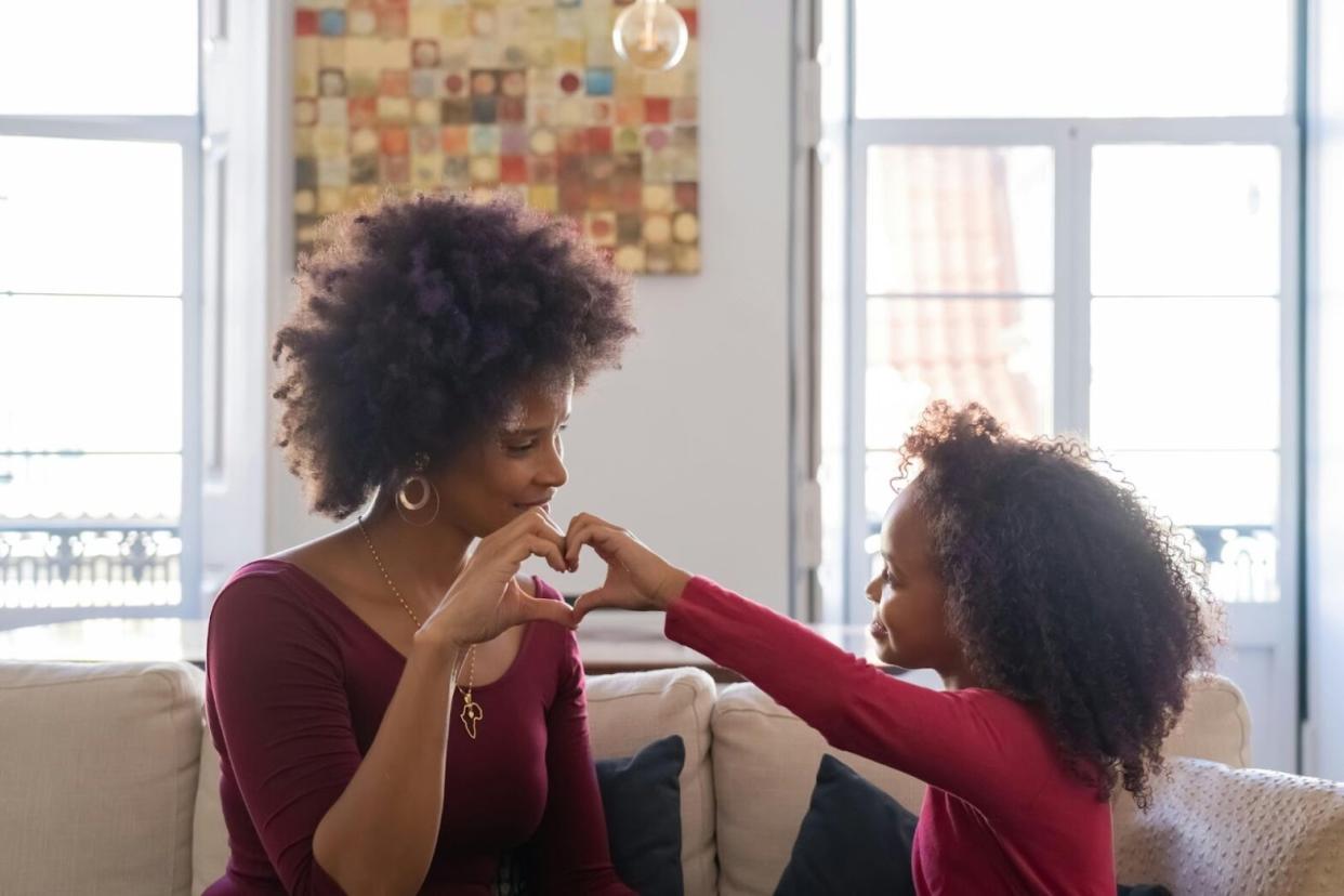 Check out these destinations that may be the perfect place to take mom for Mother's Day. pictured: a Black mother and her daughter gazing at eachother lovingly