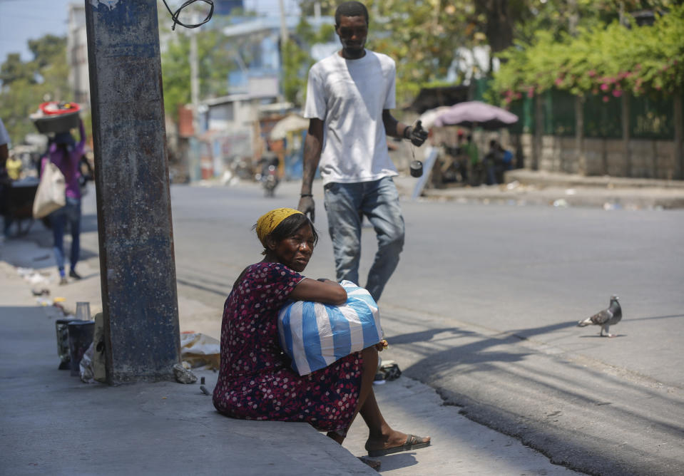 A woman sits on the side of an empty street near the National Palace in Port-au-Prince, Haiti, Monday, March 25, 2024. (AP Photo/Odelyn Joseph)