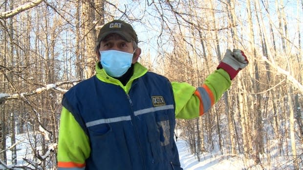 John Gonet stands in his backyard, where he used to build a snow slide for his five-year-old grandson. He stopped building it a few years ago due to a high number of bison walking through his backyard.  (Anna Desmarais/CBC North  - image credit)