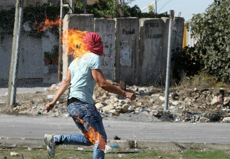 The clothes of a Palestinian student burn after he set himself on fire while throwing a Molotov cocktail towards Israeli soldiers and border police during clashes in the West Bank town of Hebron on October 13, 2015
