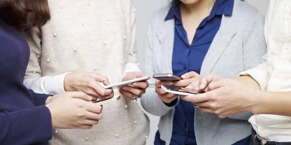 A group of four people standing around using mobile phones.