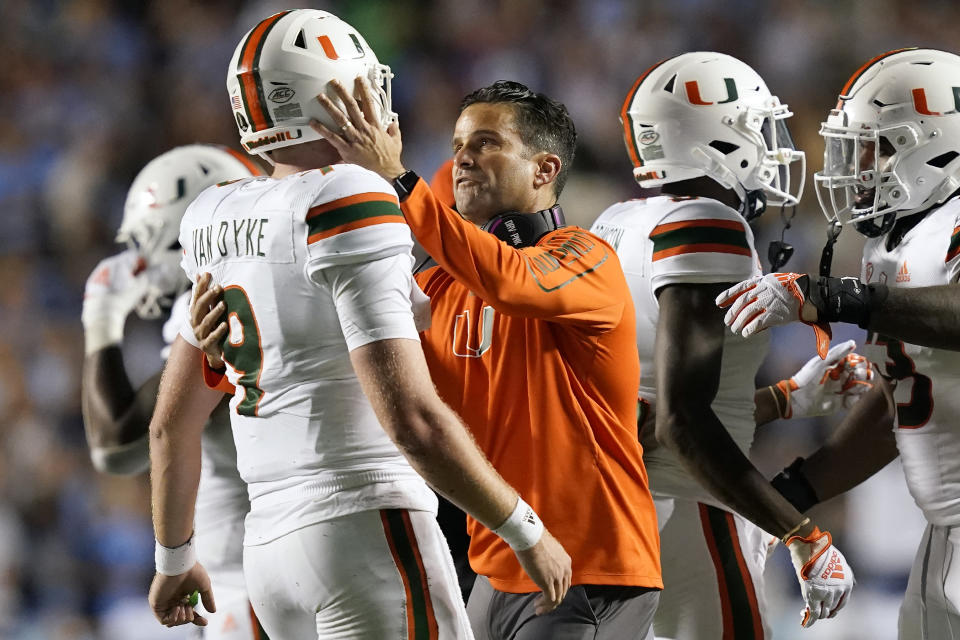 Miami head coach Manny Diaz, center, consoles quarterback Tyler Van Dyke (9) following an NCAA college football game against North Carolina in Chapel Hill, N.C., Saturday, Oct. 16, 2021. (AP Photo/Gerry Broome)