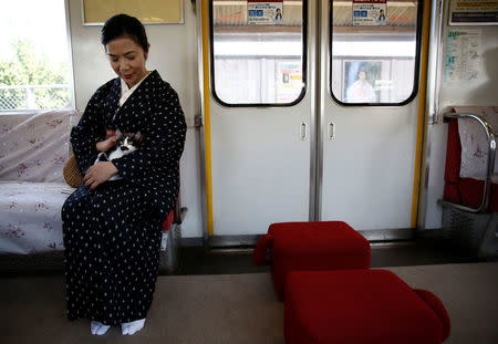 A woman wearing a Kimono holds a cat, in a train cat cafe, held on a local train to bring awareness to the culling of stray cats, in Ogaki, Gifu Prefecture, Japan September 10, 2017. REUTERS/Kim Kyung-Hoon