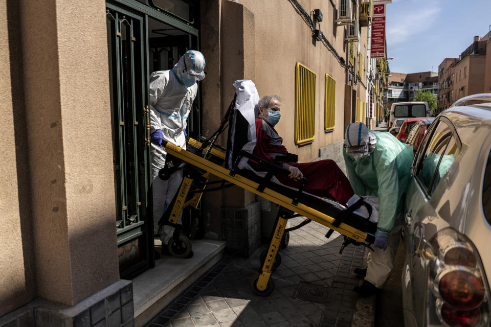 Enrique, a 92 year old man is taken out of his home by medics to a waiting ambulance after he showed signs of possible coronavirus symptoms with serious breathing problems in Madrid, Spain, Sunday, April 12, 2020. Spain will allow workers in industry and construction to return to work after a two-week shutdown of economic activities other than health care and the food industry. That lockdown has threatened to send the country into recession. (AP Photo/Olmo Calvo)