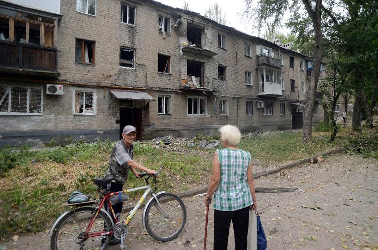 A man and a woman talk near a damaged building in the Kievski neighbourhood in northern Donetsk, eastern Ukraine on August 28, 2014