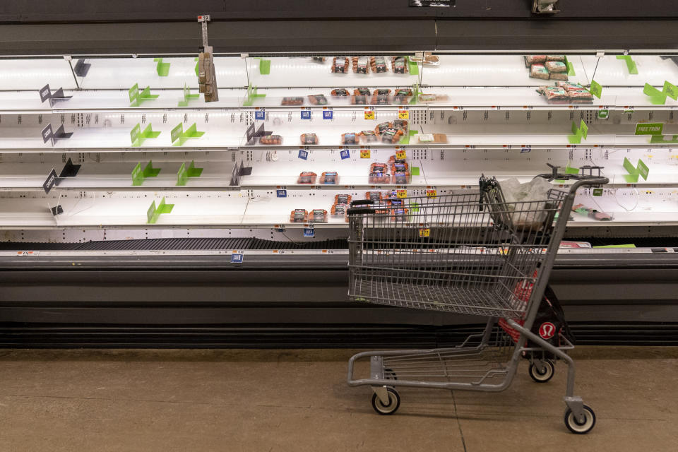 A empty shopping cart sits in front of early empty shelves of meat at a supermarket in Washington, Tuesday, Jan. 4, 2022. (AP Photo/Andrew Harnik)