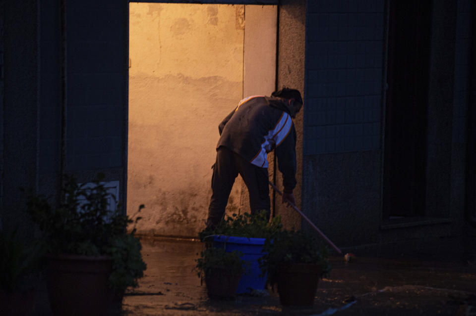 A man man tries to push water and mud out his home in Bitti, Sardinia, Italy, Saturday, Nov. 28, 2020. The town of Bitti in Sardinia was hit by a storm and flooded by a massive mudslide that killed at least 2 people on Saturday. (Alessandro Tocco/LaPresse via AP)