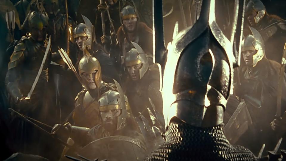 Sauron dressed in armor looks out at a group of soldiers in a scene from The Lord of the Rings: The Fellowship of the Ring.