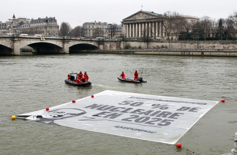 FILE - Greenpeace activists unfold a banner reading “50 percent of nuclear energy by 2025” on the Seine River in front of the National Assembly in Paris, Monday, March 9, 2015. Greenpeace accuses the French nuclear industry of fobbing off waste on other countries and covering up problems at nuclear facilities, which industry officials deny. (AP Photo/Remy de la Mauviniere, File )