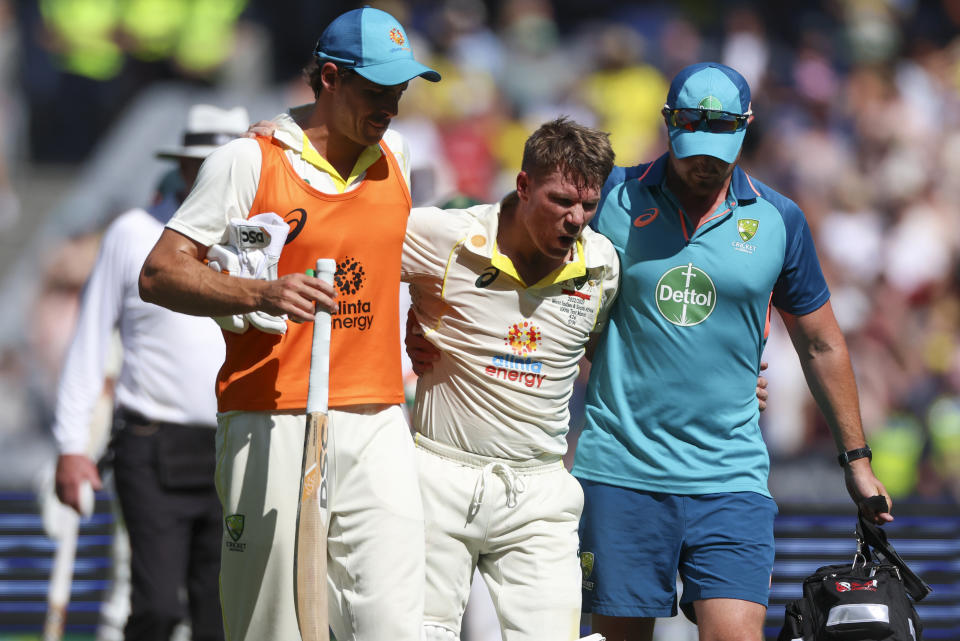 Australia's David Warner, centre, is assisted from the field as he retires injured after reaching 200 runs during the second cricket test between South Africa and Australia at the Melbourne Cricket Ground, Australia, Tuesday, Dec. 27, 2022. (AP Photo/Asanka Brendon Ratnayake)