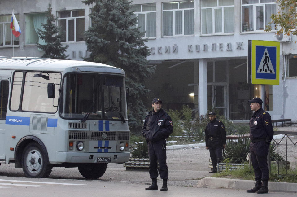 Policemen stand guard near a vocational college in Kerch, Crimea, Thursday, Oct. 18, 2018. An 18-year-old student strode into his vocational school in Crimea, a hoodie covering his blond hair, then pulled out a shotgun and opened fire on Wednesday, killing scores of students and wounding dozens of others before killing himself. (AP Photo)