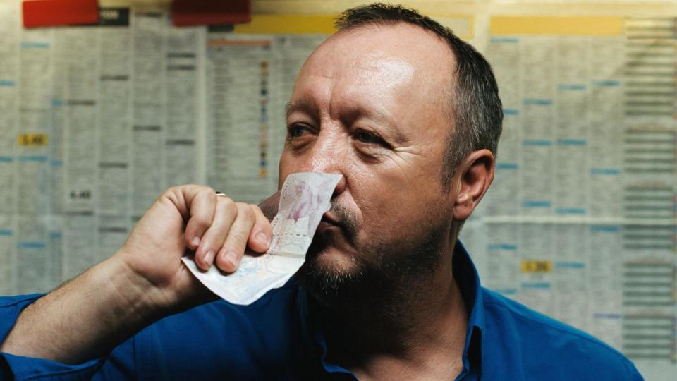 Man in bookies kissing a twenty pound note - stock photo