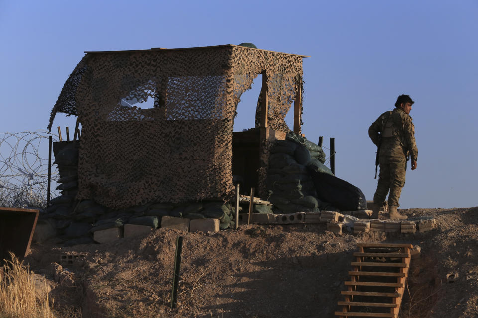 A fighter from the Syrian Democratic Forces, SDF, stands inside a post where U.S. troops were based, in Tel Abyad town, at the Syrian-Turkish border, Syria, Monday, Oct. 7, 2019. The SDF, a U.S.-backed Kurdish-led force accused Washington Monday of failing to abide by its commitments by withdrawing from northeast Syria ahead of a Turkish invasion that the Kurds say will overturn five years of achievements in the battle against the Islamic State group. (AP Photo/Ahmad Baderkhan)