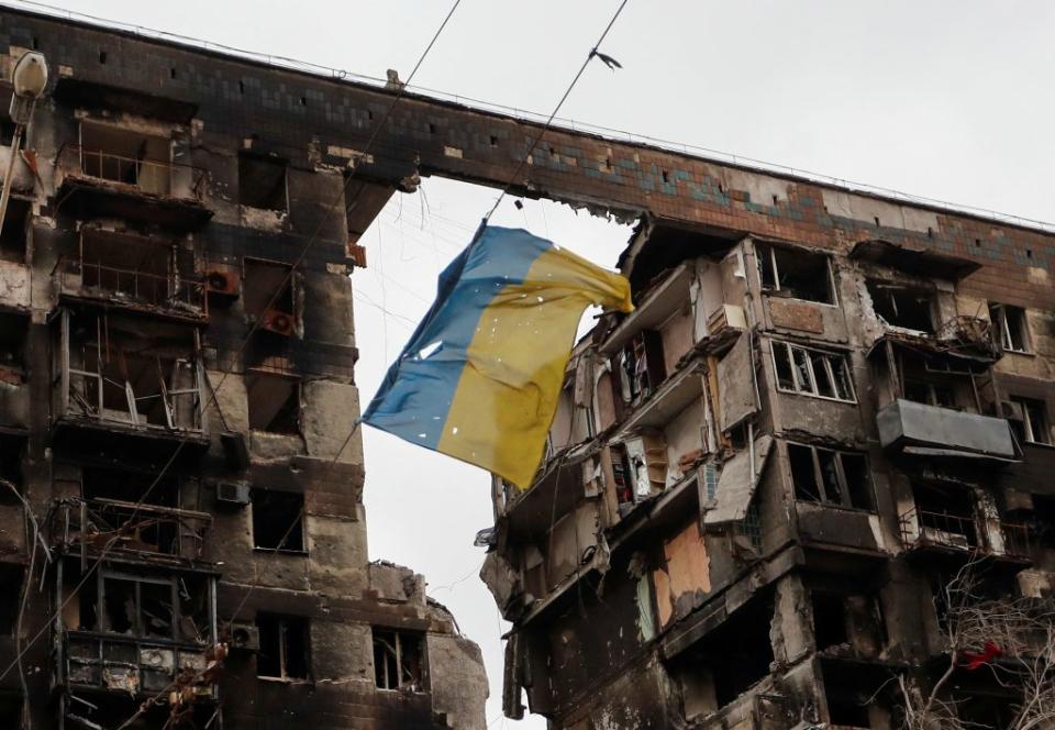 華府預估，俄烏戰爭可能持續至年底。圖為烏克蘭南部港市馬立波一座遭戰火波及的公寓，樓前的電線上掛著一面被撕毀的烏克蘭國旗。 （路透）