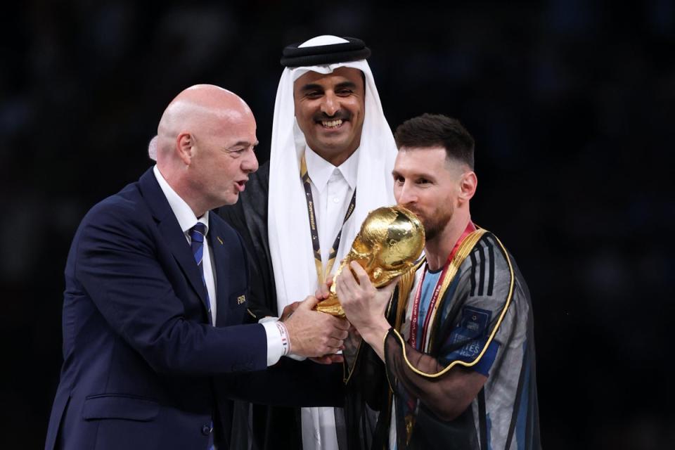 Lionel Messi of Argentina kisses the FIFA World Cup Qatar 2022 Winner’s Trophy as Gianni Infantino, President of FIFA, and Sheikh Tamim bin Hamad Al Thani, Emir of Qatar (Getty Images)
