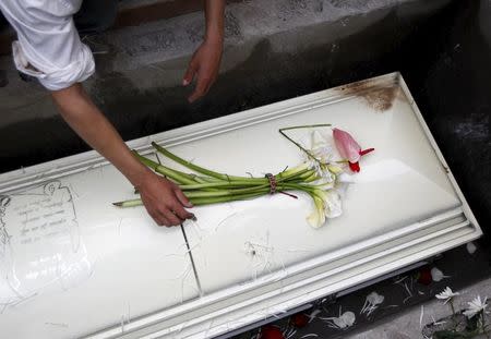 A man puts flowers on the coffin of slain environmental rights activist Berta Caceres at a cemetery in the town of La Esperanza, outside Tegucigalpa, Honduras March 5, 2016. REUTERS/Jorge Cabrera