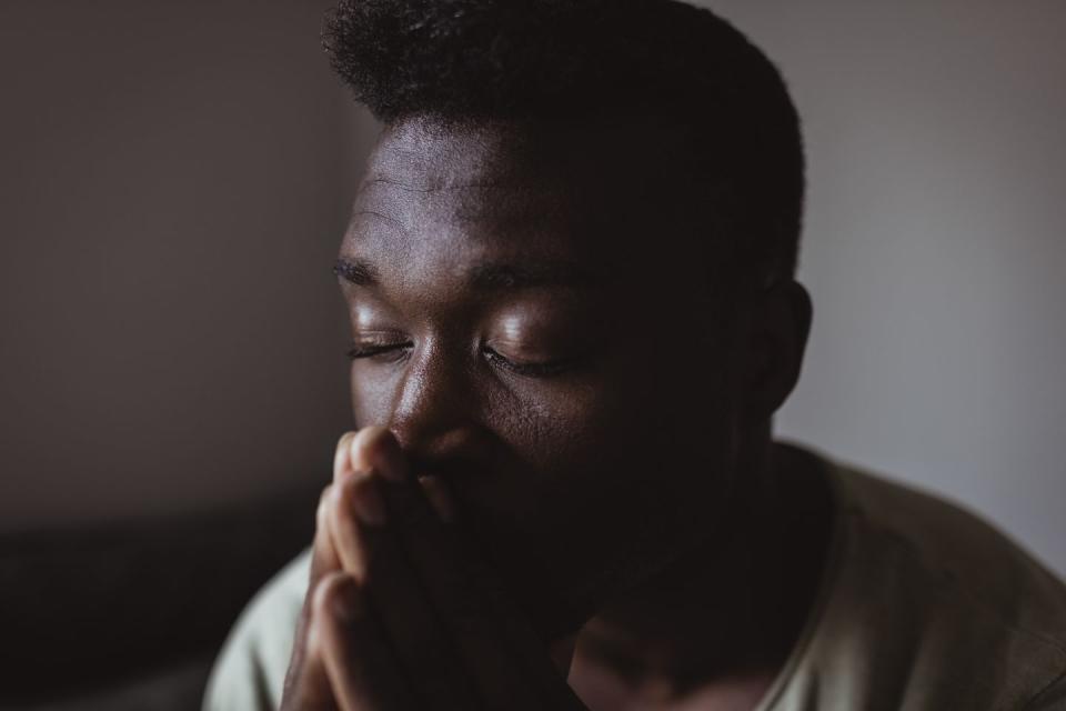 close up of worried man with eyes closed at home