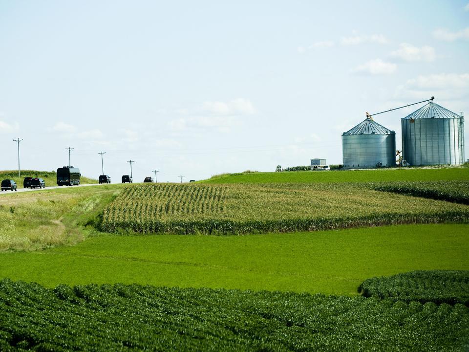 Trucks and busses driving through farmland in Harmony, Minnesota.