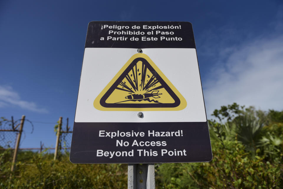 This Jan. 13, 2017 photo a no access warning sign stands at Verdiales Key point on the south coast of Vieques island, Puerto Rico. Tons of unexploded bombs, rockets and other munitions still lie scattered across the eastern half of the island and the surrounding seabed. (AP Photo/Carlos Giusti)