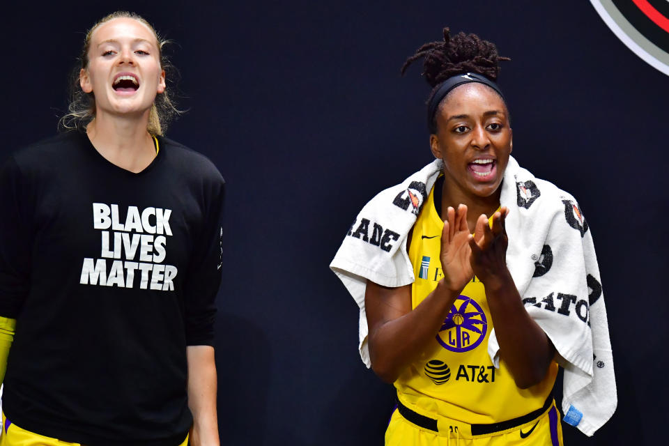 Marie Gulich to the left in a black Black Lives Matter shirt. Nneka Ogwumike in a jersey, clapping on the bench.