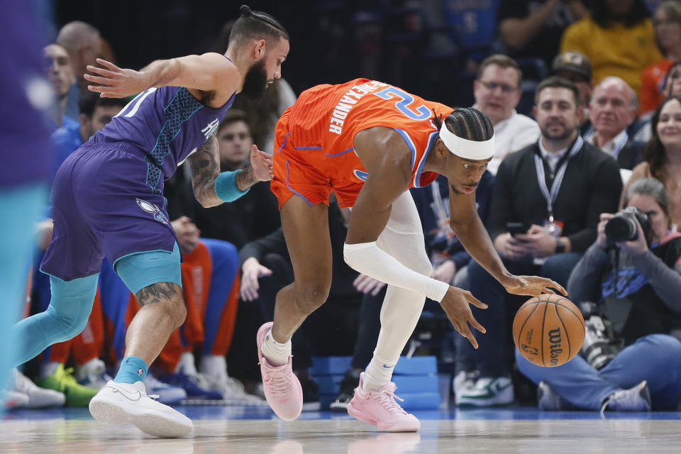 Oklahoma City Thunder guard Shai Gilgeous-Alexander (2) grabs the ball next to Charlotte Hornets forward Cody Martin, left, during the first half of an NBA basketball game, Friday, Feb. 2, 2024, in Oklahoma City. (AP Photo/Nate Billings)