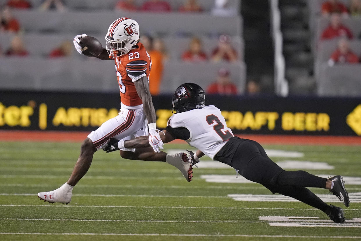 Southern Utah cornerback Devyn Perkins (2) reaches for Utah running back Dijon Stanley (23) in the second half of an NCAA college football game Thursday, Aug. 29, 2024, in Salt Lake City. (AP Photo/Rick Bowmer)